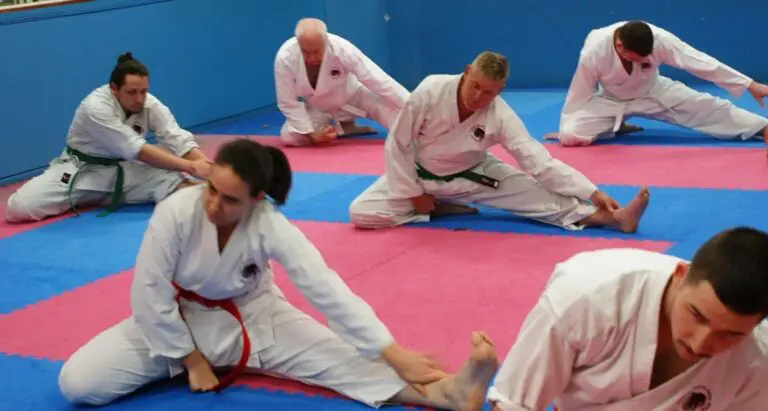 Martial arts students stretching on training mats during karate warm-up session.