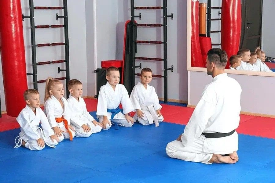 martial arts students listening to instructor while sitting on mat