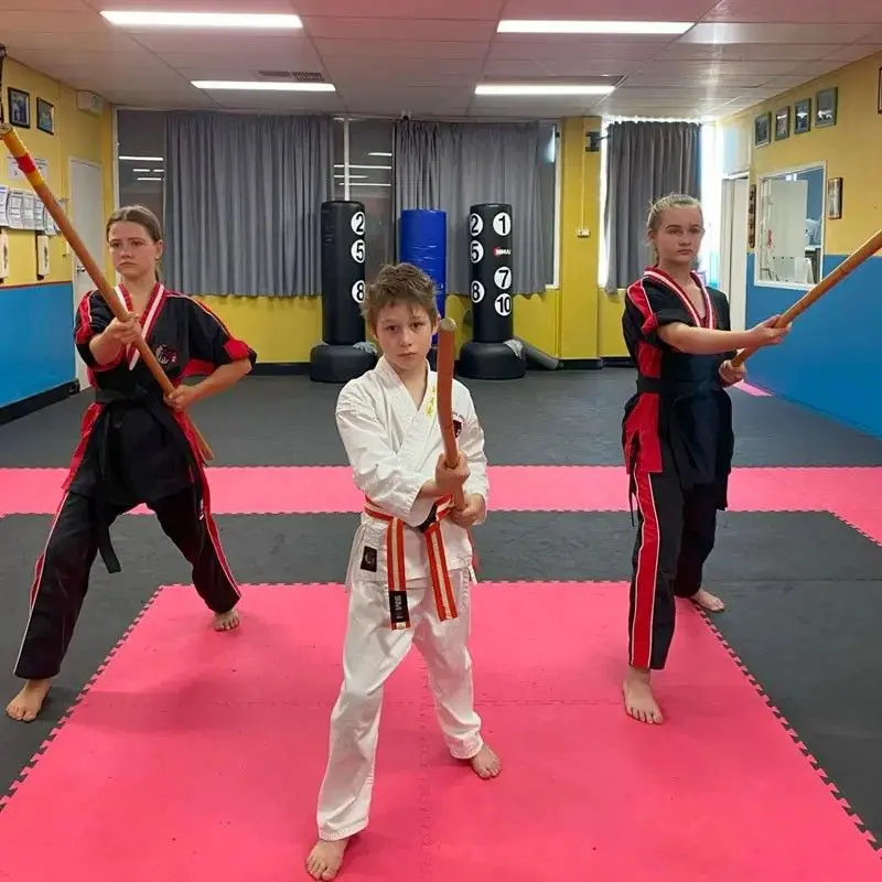 Kids learning bo staff techniques during martial arts weapons training